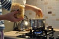 A young housewife is preparing dinner, next to a large steel pot