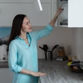 Young housewife puts clean dishes on the drying rack shelf in white kitchen interior, household chores concept