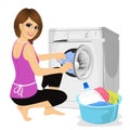 Young housewife putting a cloth into washing machine