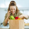 Young housewife sort purchases after shopping and talking cell p Royalty Free Stock Photo