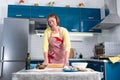 Young housewife woman in apron, rolls out pizza dough. Indoor. The concept of a home-cooked meal Royalty Free Stock Photo