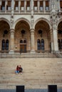 Young hugging couple is holding hands and sitting on the stairs of the old historic building in Budapest, Hungary.