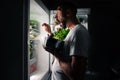 Young hungry man eating food at night from open fridge. Midnight snack and food addiction