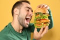 Young hungry man eating huge burger