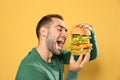 Young hungry man eating huge burger