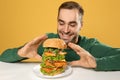 Young hungry man eating huge burger