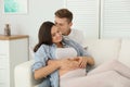 Young husband and his pregnant wife resting on sofa Royalty Free Stock Photo