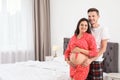 Young husband hugging his lovely pregnant wife in bedroom. Royalty Free Stock Photo