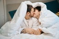 Young husband and wife kiss cute under the covers