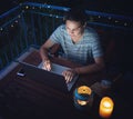 Young hysster woman working on a laptop in the evening on the open terrace of her country house, cozy with candles and lanterns Royalty Free Stock Photo