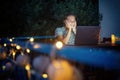 Young hysster woman working on a laptop in the evening on the open terrace of her country house, cozy with candles and lanterns Royalty Free Stock Photo