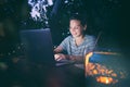 Young hysster woman working on a laptop in the evening on the open terrace of her country house, cozy with candles and lanterns Royalty Free Stock Photo