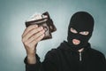 Young ill-intended man wearing black mask holds the black leather men purse and looks to his loot. Robber has stolen the wallet. Royalty Free Stock Photo