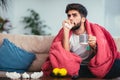 Ill man drinking hot tea at home and watching tv Royalty Free Stock Photo
