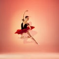 Young and incredibly beautiful ballerina is posing and dancing at red studio full of light. Royalty Free Stock Photo