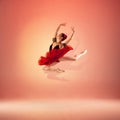 Young and incredibly beautiful ballerina is posing and dancing at red studio full of light. Royalty Free Stock Photo