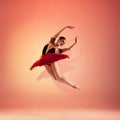 Young and incredibly beautiful ballerina is posing and dancing at red studio full of light. Royalty Free Stock Photo