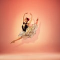 Young and incredibly beautiful ballerina is posing and dancing at red studio full of light. Royalty Free Stock Photo