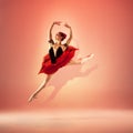 Young and incredibly beautiful ballerina is posing and dancing at red studio full of light. Royalty Free Stock Photo