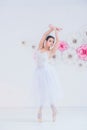 Young and incredibly beautiful ballerina is posing and dancing in a white studio full of light.