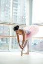 Young and incredibly beautiful ballerina is posing and dancing in a white studio full of light.