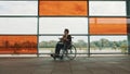 Young independed caucasian woman in the wheeldchair reading a book in front of big glass multicoloroed windows