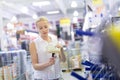 Young independent woman buying tools for house decoration in paint supplies shop.