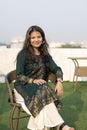 Young indian beautiful girl posing towards the camera, while sitting on the chair. Girl wearing indian traditional dress Royalty Free Stock Photo