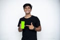 Young indian boy holding a mobile phone and point towards it`s screen. Mobile phone with a green screen for mockup Royalty Free Stock Photo