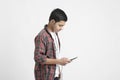 Young indian boy listening music and using smartphone on white background Royalty Free Stock Photo