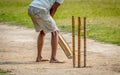 A young Indian boy playing cricket. View of a right handed batsman with all three stumps visible