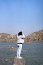 Young indian boy standing on a cliff near a landscape of a lake and mountain in the background Royalty Free Stock Photo