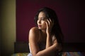 Young Indian brunette woman in sleeping wear sitting on a bed Royalty Free Stock Photo