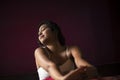 Young Indian brunette woman in sleeping wear sitting on a bed Royalty Free Stock Photo