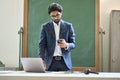 Young indian business man using phone working on laptop in office. Royalty Free Stock Photo