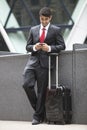 Young Indian businessman with luggage bag using cell phone Royalty Free Stock Photo