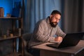 Young indian businessman using a laptop and writing notes while working overtime at his office desk late in the evening Royalty Free Stock Photo