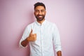Young indian businessman wearing elegant shirt standing over isolated pink background doing happy thumbs up gesture with hand Royalty Free Stock Photo