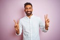 Young indian businessman wearing elegant shirt standing over isolated pink background smiling looking to the camera showing Royalty Free Stock Photo