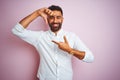 Young indian businessman wearing elegant shirt standing over isolated pink background smiling making frame with hands and fingers Royalty Free Stock Photo