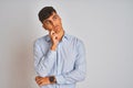 Young indian businessman wearing elegant shirt standing over isolated white background with hand on chin thinking about question, Royalty Free Stock Photo