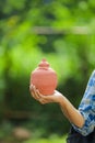 Young indian college boy holding clay piggy bank in hand over nature background Royalty Free Stock Photo