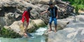 Young Indian couple in forest by the stream. Husband and wife walking on the rocks by the mountain stream. Man helping his Royalty Free Stock Photo