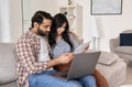 Young indian couple reading bills paying online using laptop at home. Royalty Free Stock Photo