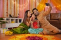 Young Indian couple with their daughter celebrating diwali at home - Indian festival, hindu festival.