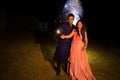 Young Indian couple in traditional wear celebrating holding sparklers, firecrackers or phuljhadi in hand as a part of diwali Royalty Free Stock Photo