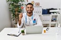 Young indian doctor holding reflex hammer looking positive and happy standing and smiling with a confident smile showing teeth Royalty Free Stock Photo