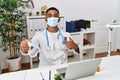 Young indian doctor offering safety mask pointing finger to one self smiling happy and proud Royalty Free Stock Photo