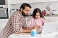 Young indian father helping school child teen daughter studying online at home.