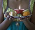 Young Indian Female dressed in traditional clothes Carrying Indian Diwali Sweets